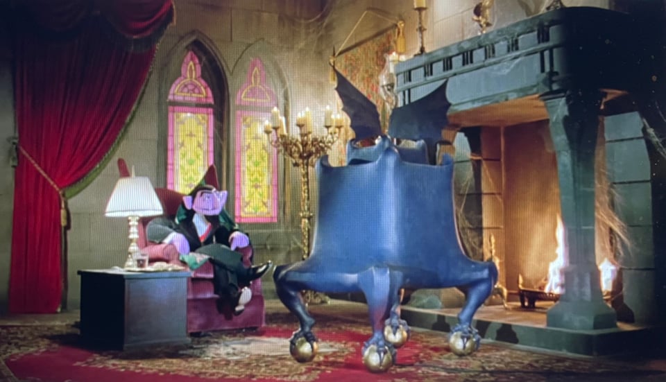 A shot from the film Follow That Bird. The Count, a vampire muppet, sits in his castle watching his extremely gothic TV set that has bat wings