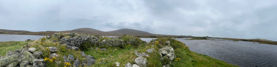 Panoramic shot of Dun an Sticir, taken from behind the broch and facing the other two islands. You can see the causeways half-sunk in the swollen loch. The inside of the broch is grassy.