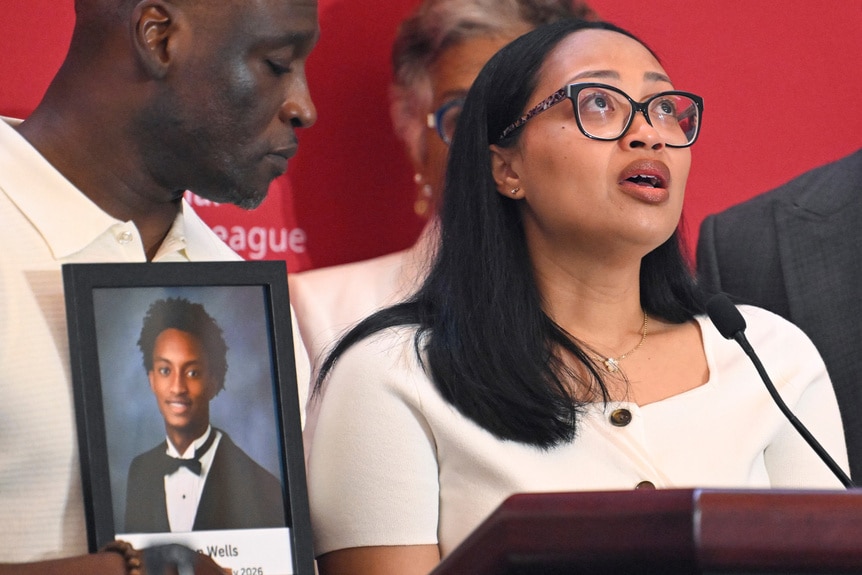 Nolan's mom speaking behind a podium at a press conference