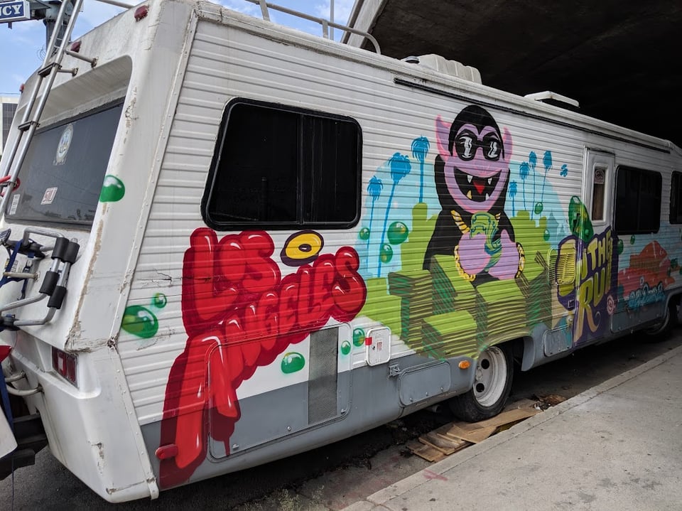 A camper van painted with LOS ANGELES plus the Count from Sesame Street counting piles of dollar bills