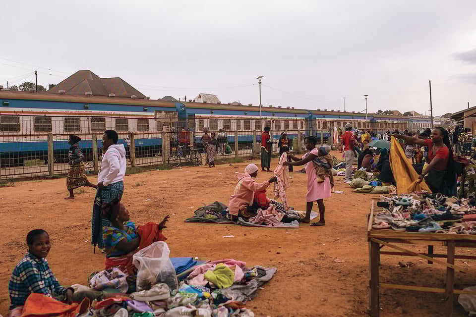 People set up street stalls next to a train