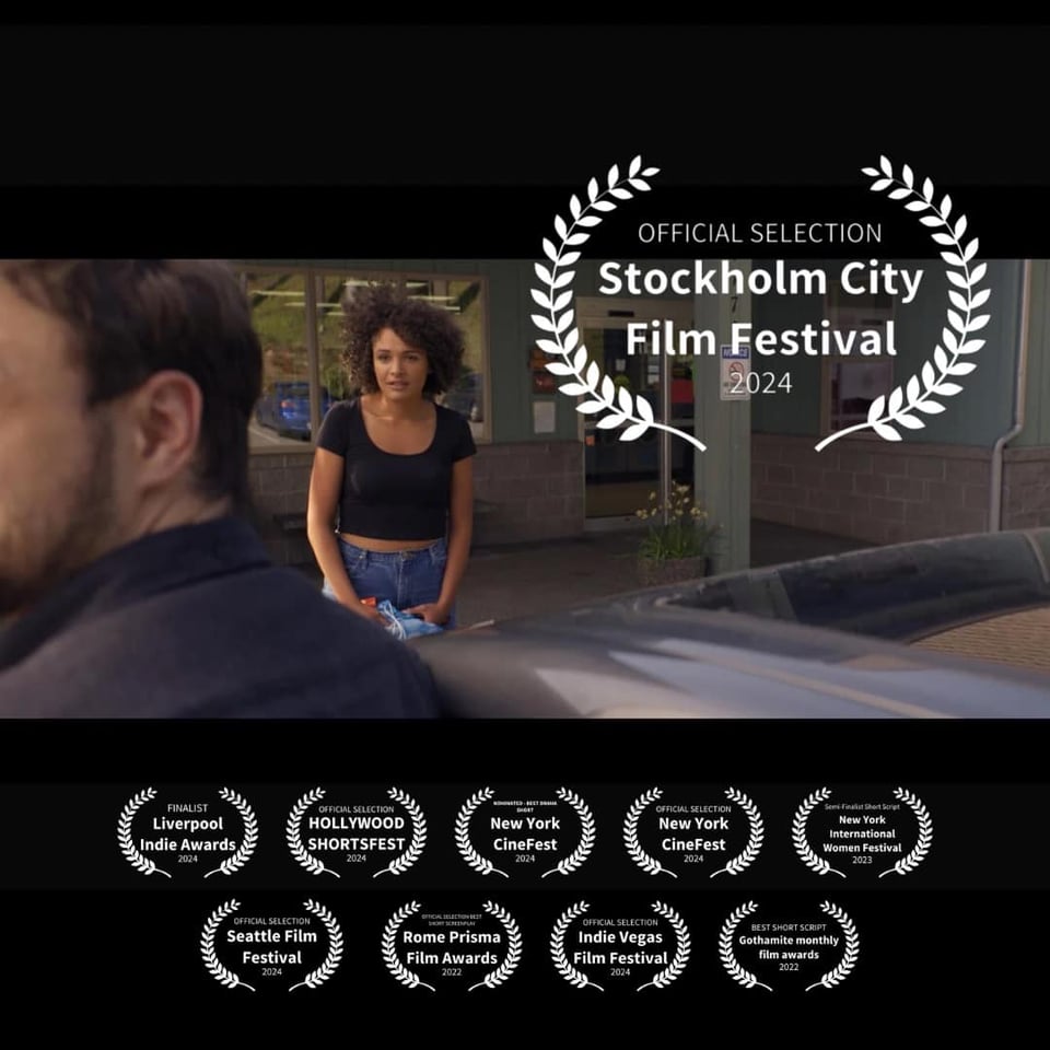 Still from Elvis of the Yukon, a woman looks at a man who is turned away from her -- the image is covered with award mentions.