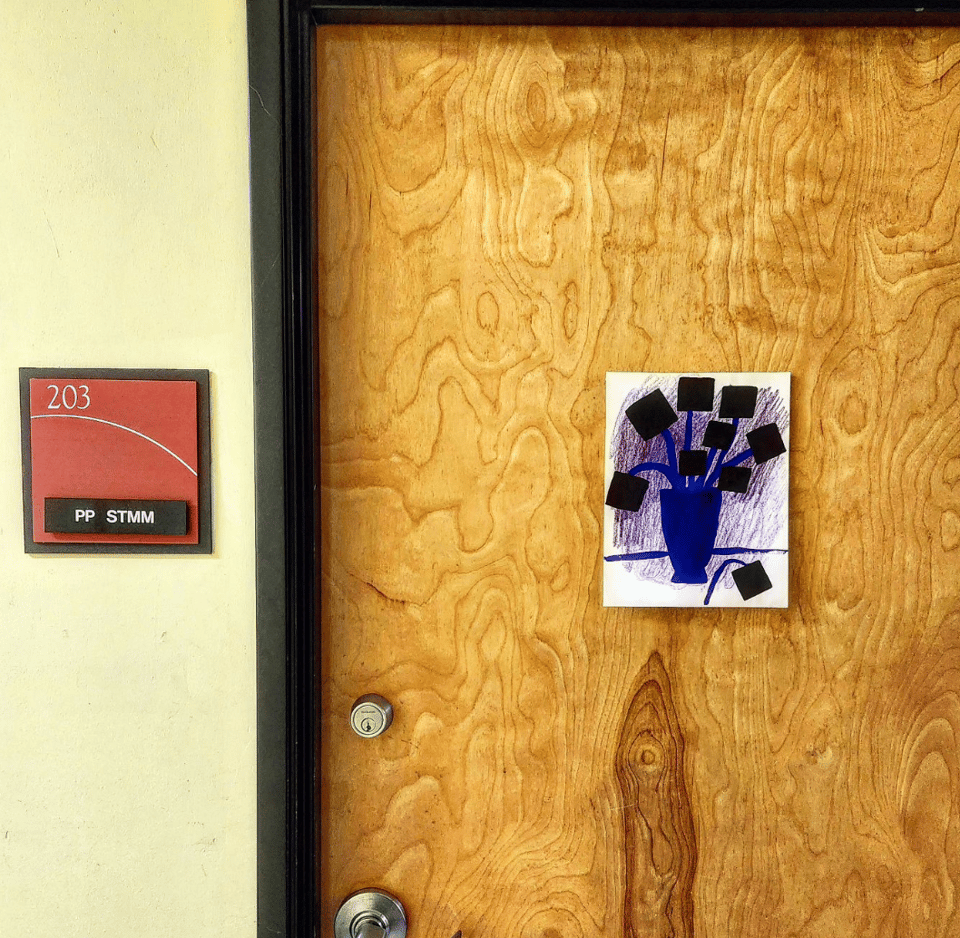 an abstract picture of blue and purple flowers in a vase, pinned to a wooden office door