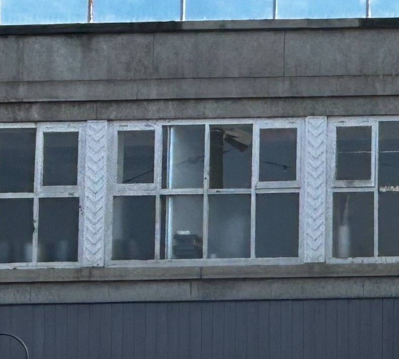 A close up of the mullions within the ribbon windows. These are painted white, and have a downwards chevron pattern on them.