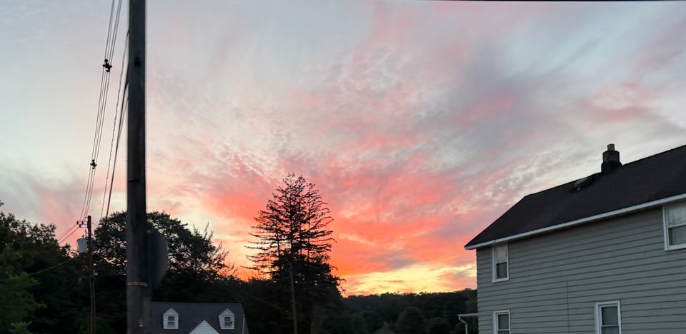 photo of varicolored sunset from suburban street with house in foreground