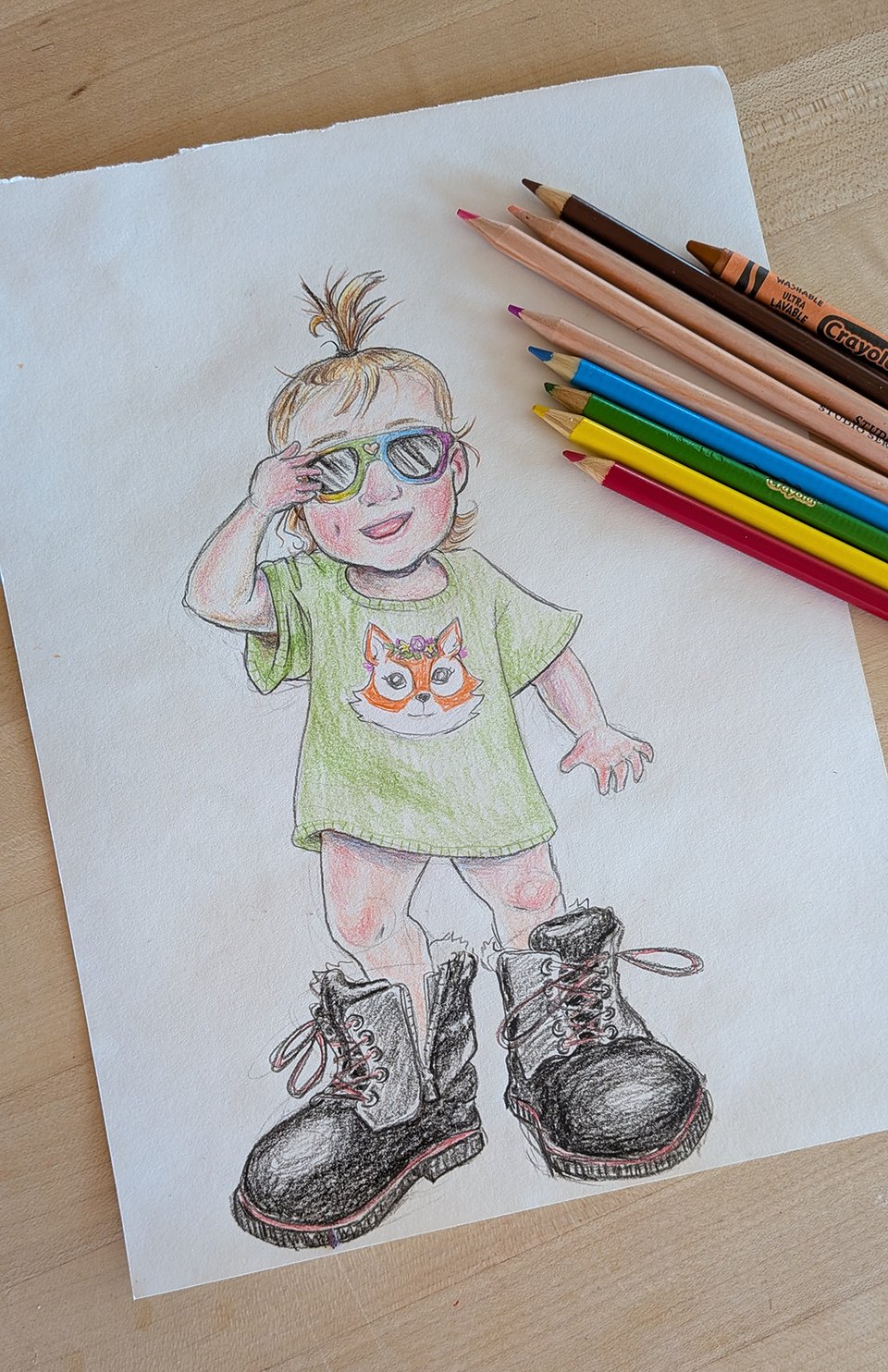 A loose colored pencil drawing of a young toddler with rainbow sunglasses, a hair sprout, oversize tee, bare legs, and gigantic adult-sized black winter boots. She is grinning and grabbing her sunglasses with one hand. She is minutes away from peeing in my boots. There's a collection of colored pencils and a crayon laying across one corner of the page to show what tools were used to create this sketch.