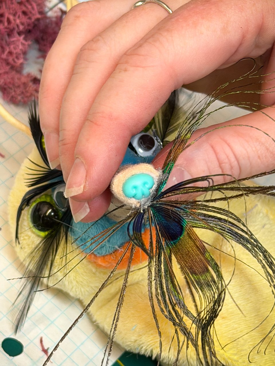 a person attaching feathers to a stuffed animal