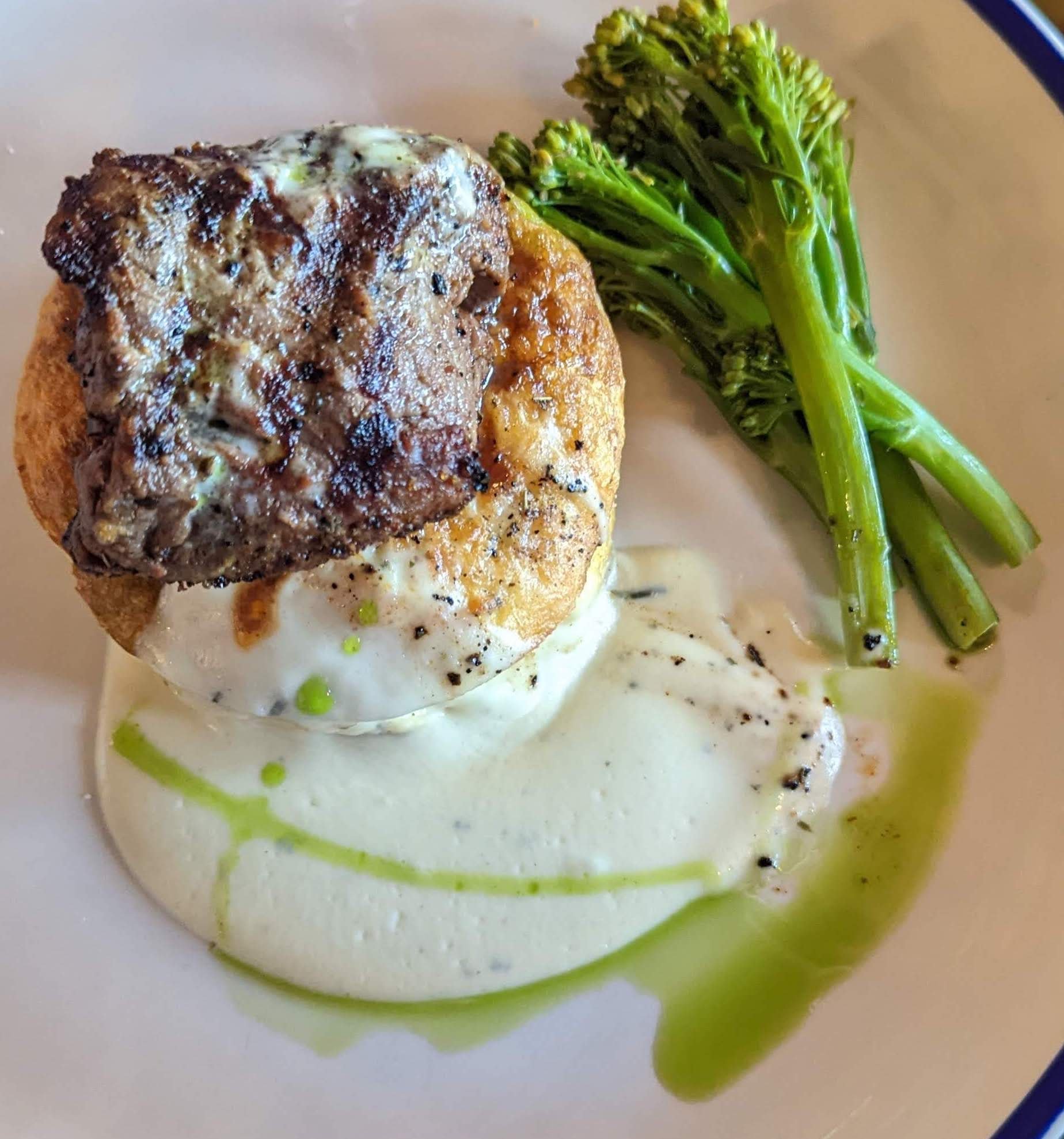 Potato and cheese frittata, hiding under breakfast beef tenderloin, surrounded by creamy sauce and brocolini