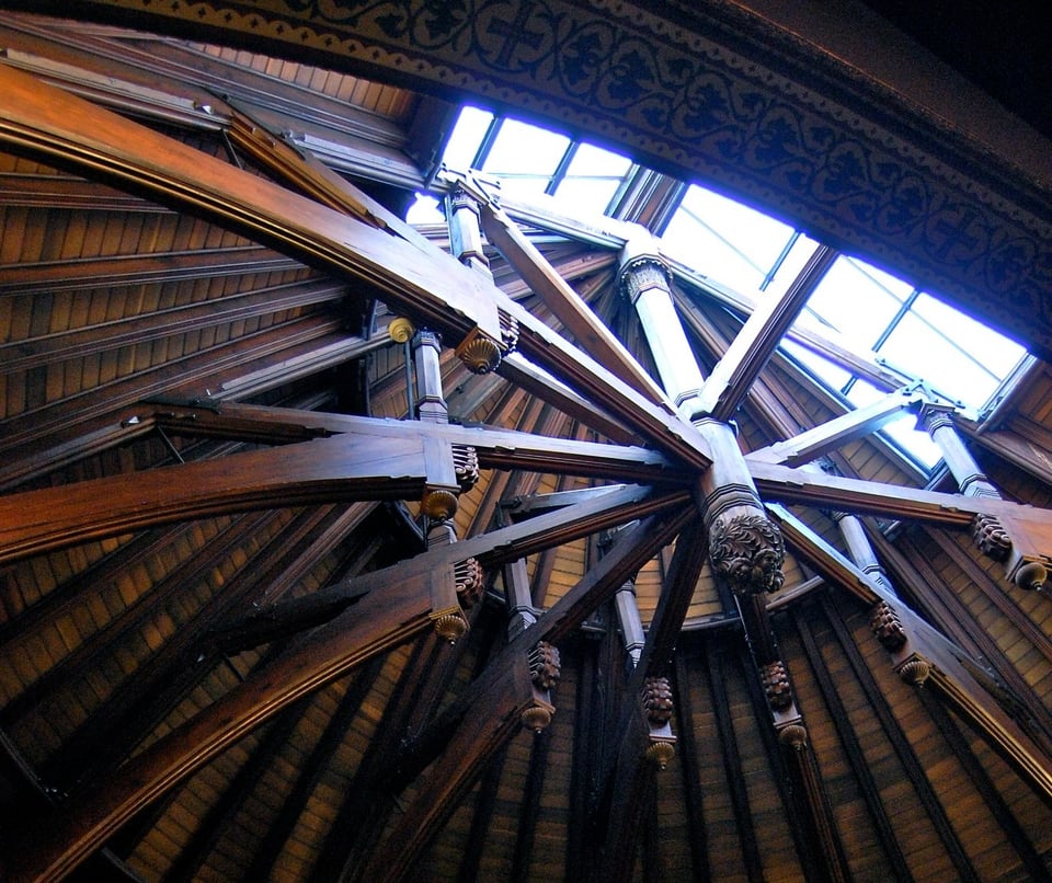 A photograph looking up in a church in which the roof is lined with large wooden beams in arches