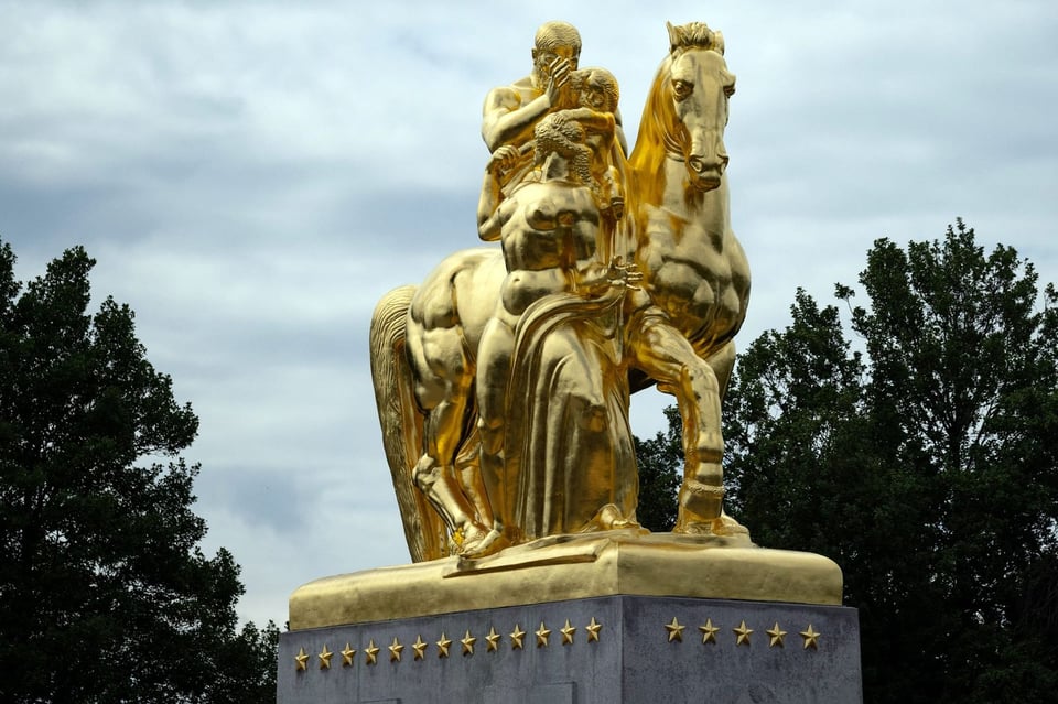 a statue of a man on a horse next to a person all covered in gold