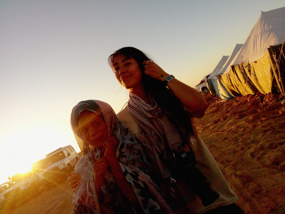 I stand with a young girl, who is covering her hand with a scarf. A ray of light can be seen behind us.