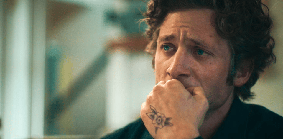 A white man with shockingly blue eyes looks at someone off camera with quiet devastation and understanding. He deserves an award.