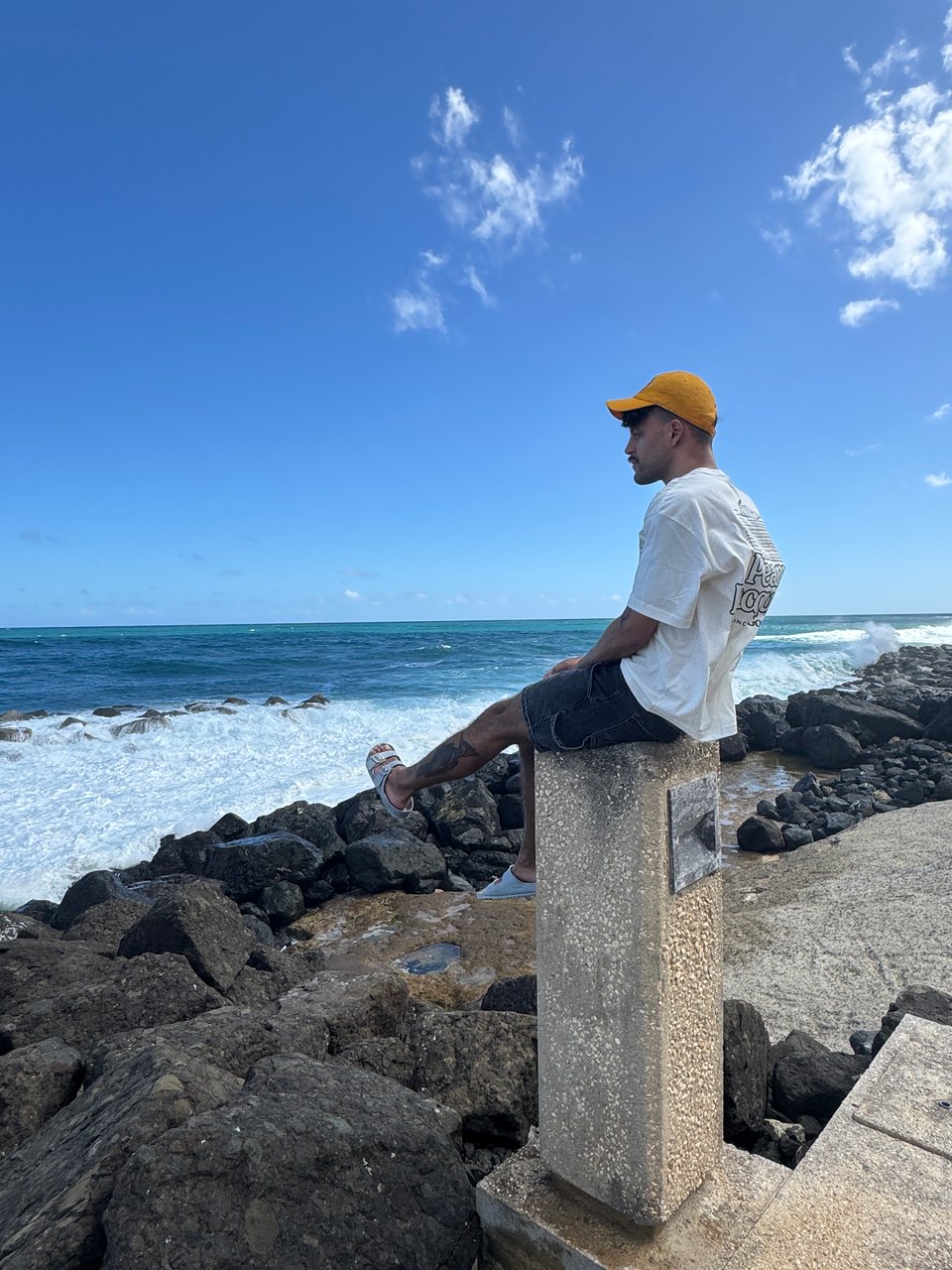 photo of me sitting on a concrete pathway lightpost overlooking the Atlantic Ocean, at San Juan National Historic Site.