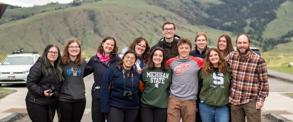 Photo shows a group of JMC students from the Yellowstone study away program. They are posing together as a group with their arms linked smiling at the camera.