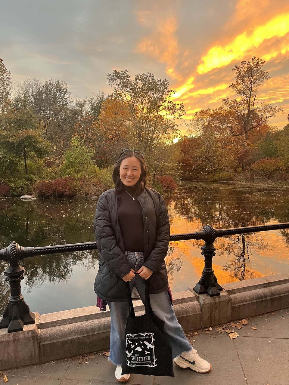 Me standing in front of a sunset lake in Prospect Park, the sky lit like it's full of fury and has got somewhere to be