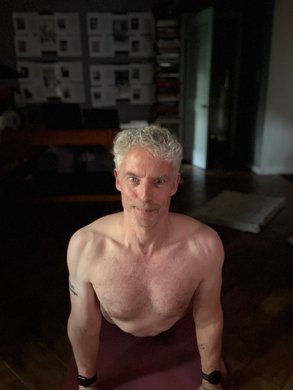 head-on photo of shirtless white man in cobra pose; he has an intense exertion-smile, and his shoulders look jacked