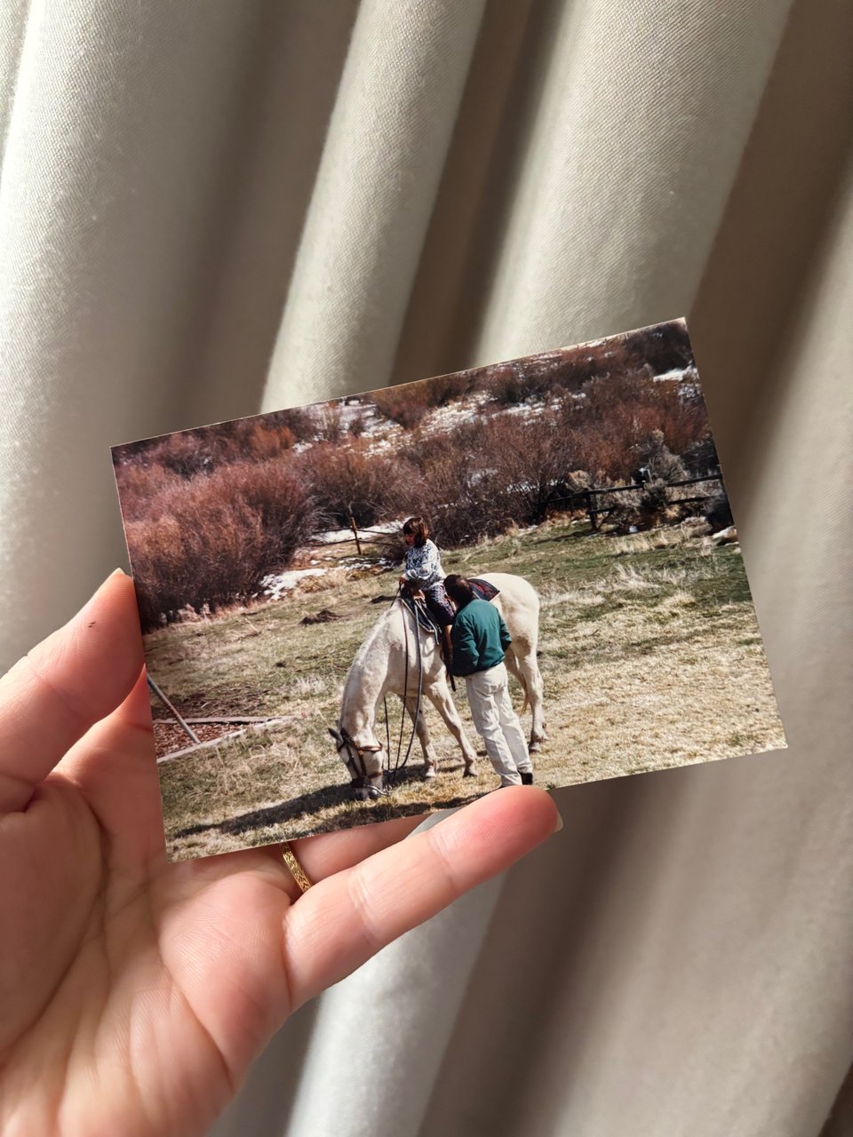 me holding a photograph of my younger self riding a friend's horse in Elko
