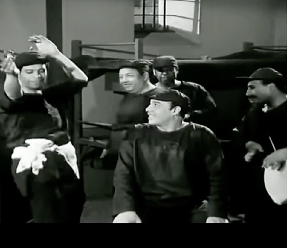 A man about to be freed from prison dances as his cellmates look on with smiles.