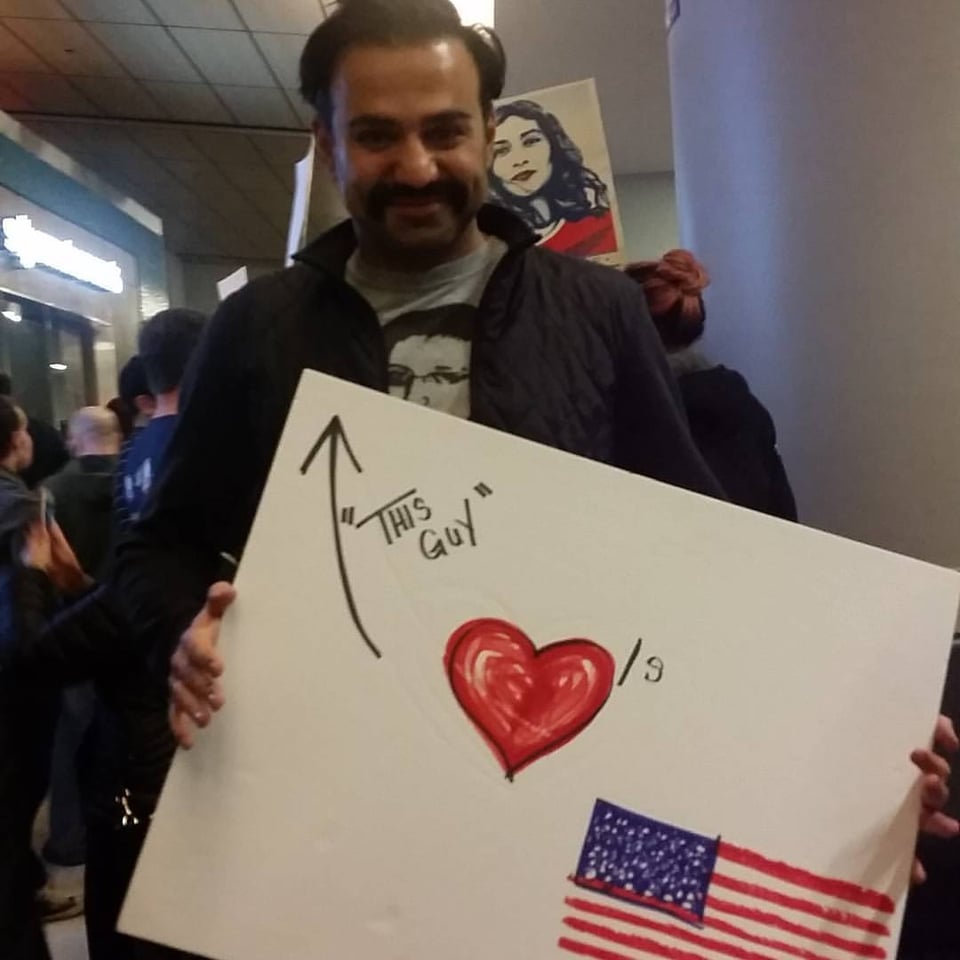 A Muslim ban during Trump's travel ban holding a sigh that says