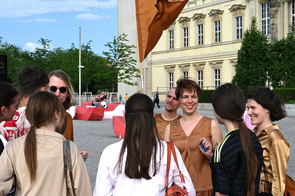 Foto von mehreren Vereinsmitgliedern im Gespräch mit Passant:innen vor dem Schloss-Neubau