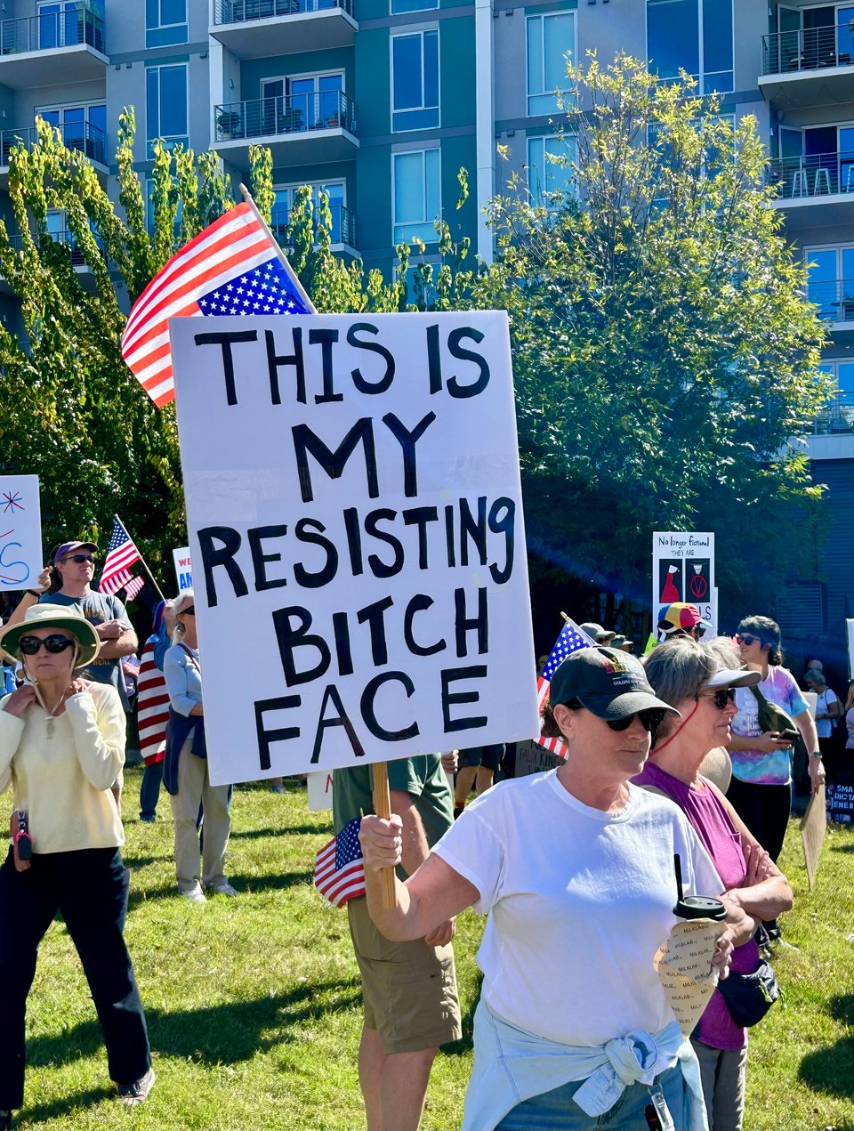 Photo of multiple protesters, including a woman with a sign that reads: "THIS IS MY RESISTING BITCH FACE."