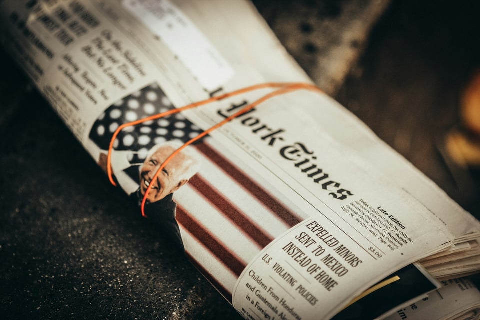 A close-up photo of a print copy of The New York Times, bound by a rubber band. Photo by Jon Tyson on Unsplash