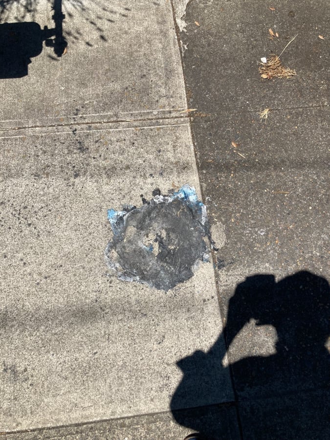 A puddle of plastic fused to the sidewalk after a trash bin melted