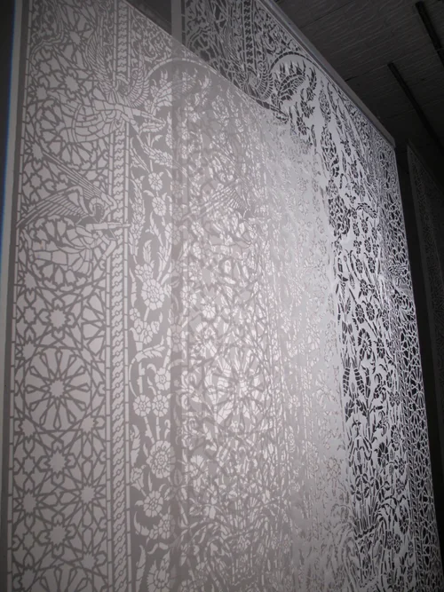 Afruz Amighi, an Iranian sculptor in Brooklyn, took that further. Her piece "Angels in Combat" looks like a traditional Persian carpet pattern, but it's cut from the polyethylene the UN uses for refugee tents. Backlit, it casts shadows on the wall. Look closer and the angels are holding rifles.