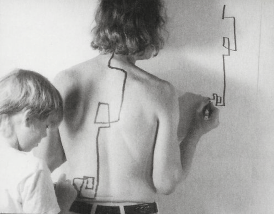 a black and white image with a person drawing lines and shapes on a wall and a young person standing behind drawing the same image on the person's back