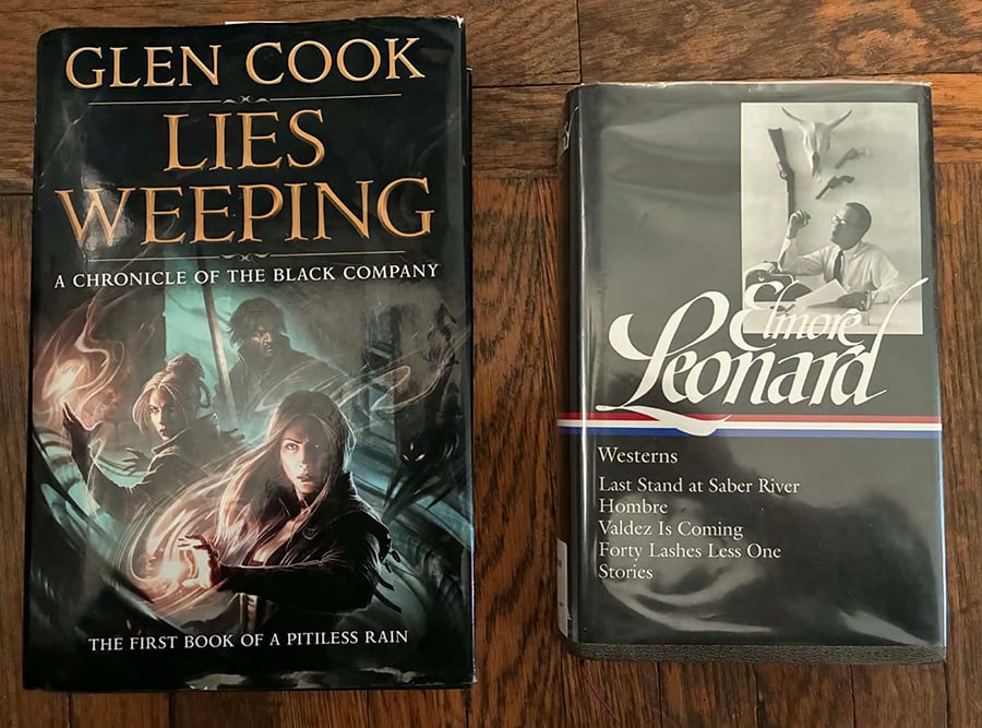 A photo of two books: Lies Weeping, by Glen Cook, and Westerns by Elmore Leonard.