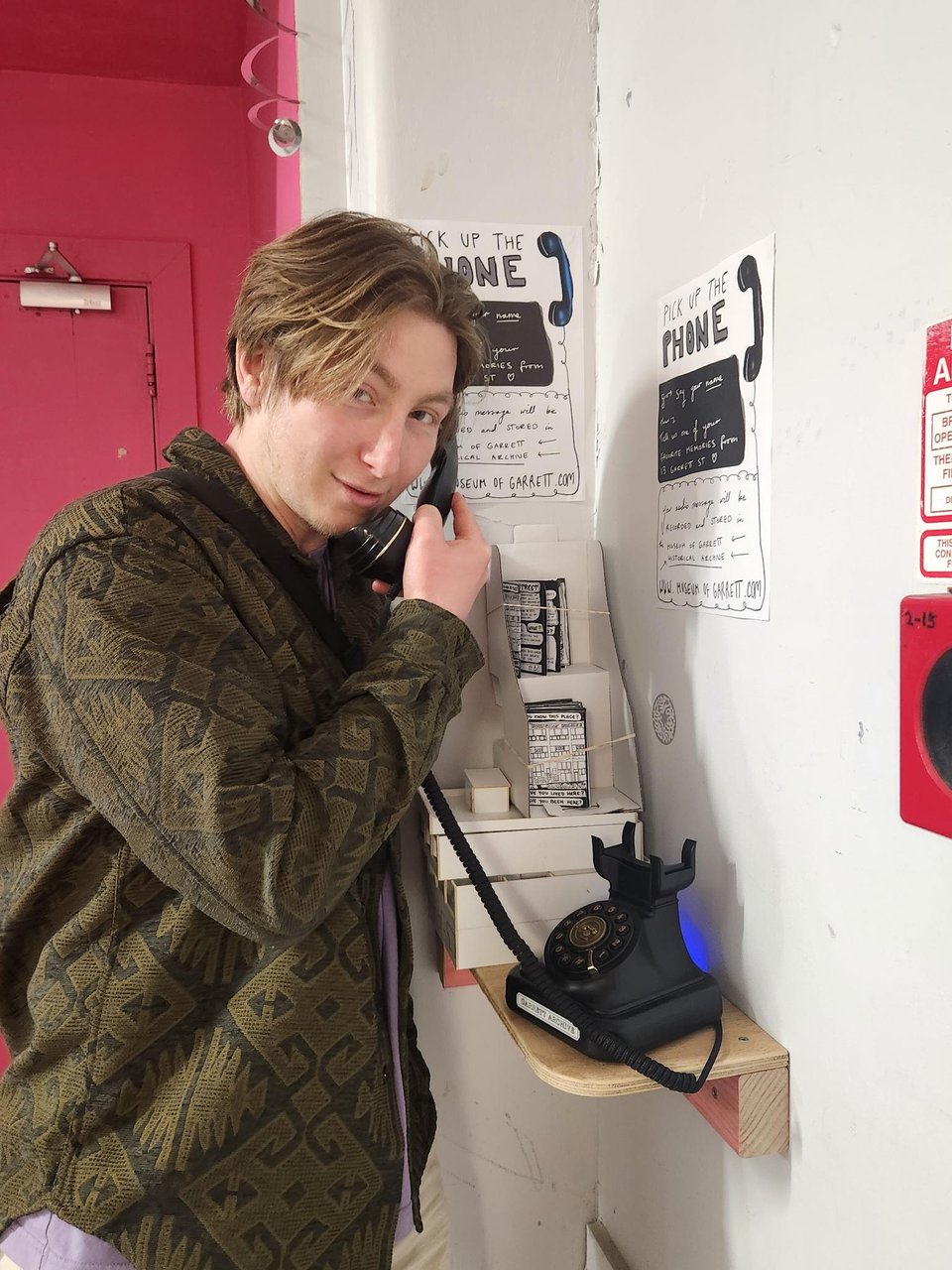 A young man holds the phone receiver to his ear.