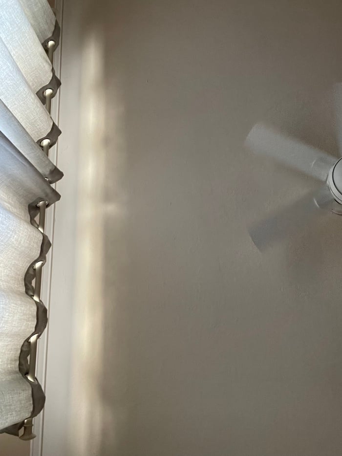 a curtain, a white ceiling and a ceiling fan