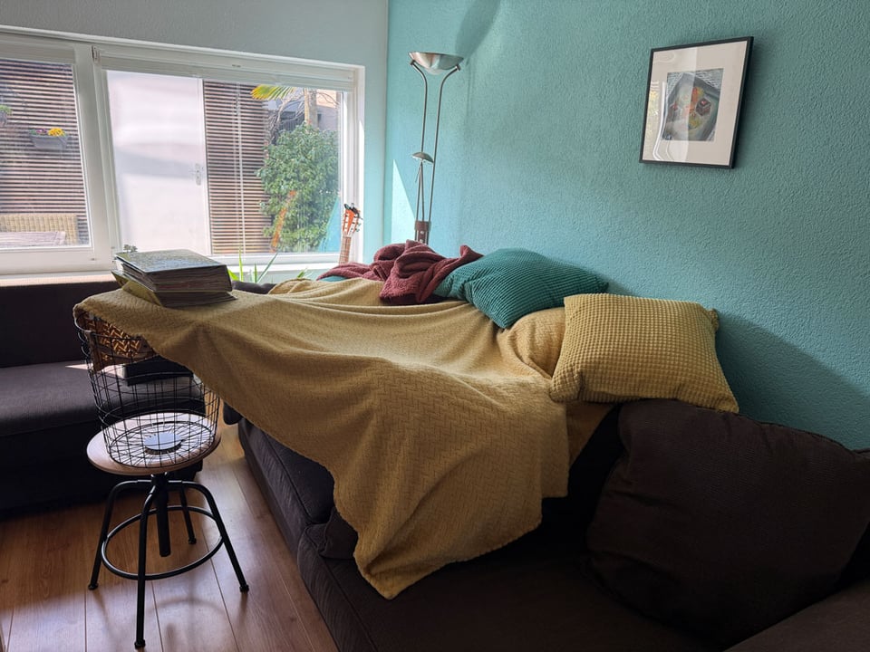 Blankets and pillows are piled up on a couch in a home-made child's fort.