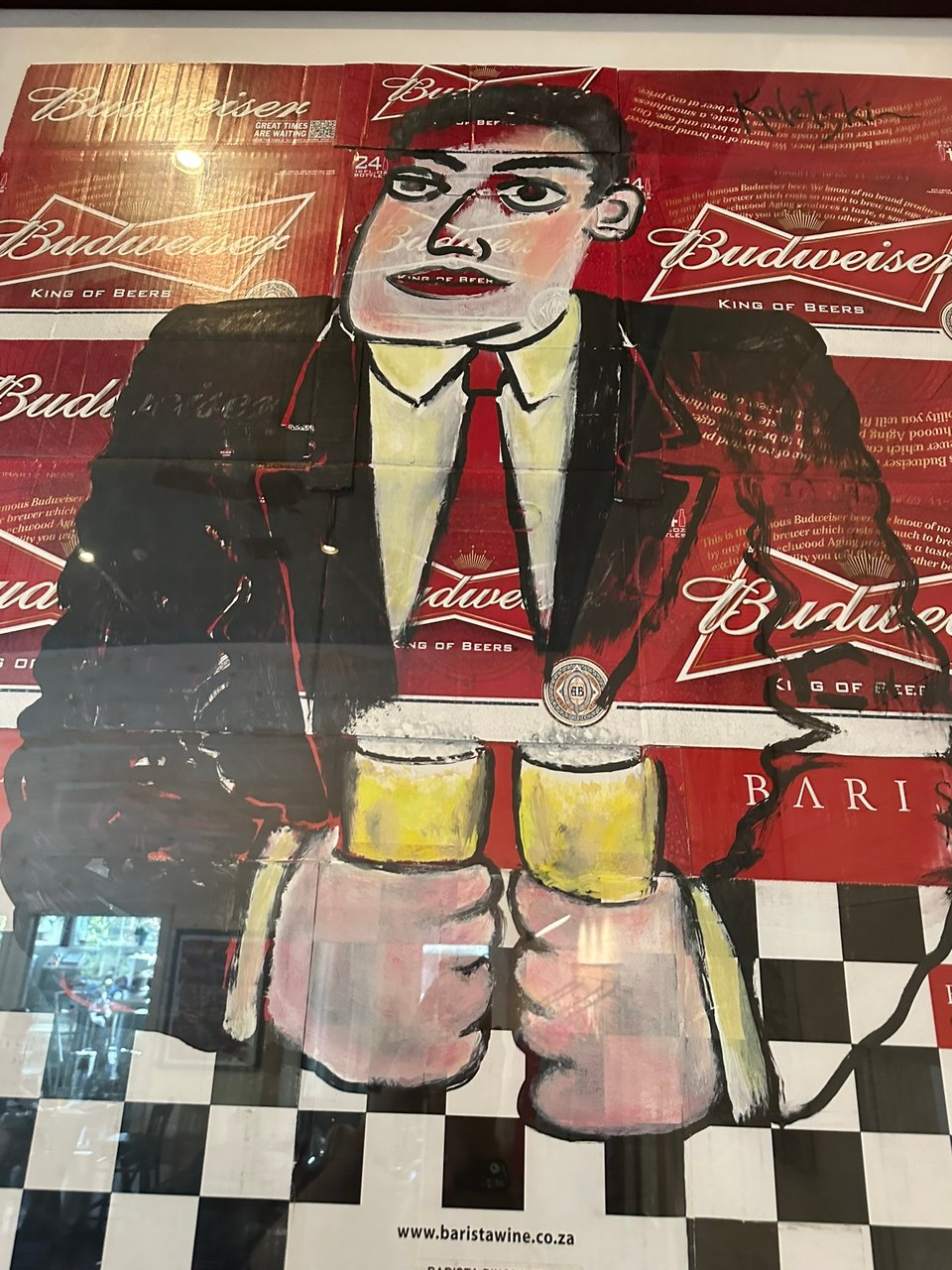 Photo of framed painting by Alexander Kaletski of a man in a black suit holding 2 beers. It is painted on Budweiser boxes