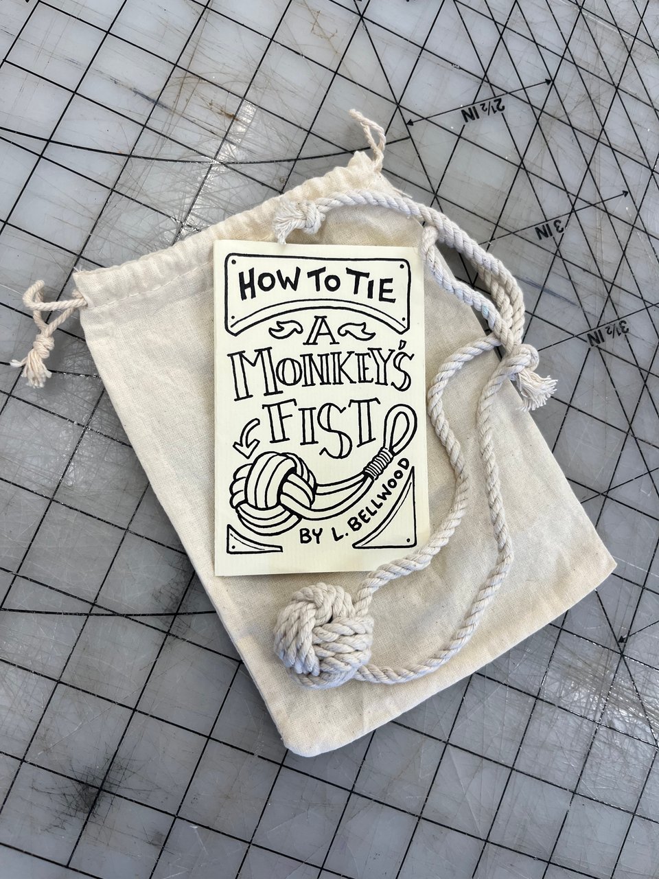 A small folded zine titled How to Tie a Monkey's Fist with an actual round knotted Monkey's Fist draped around it.