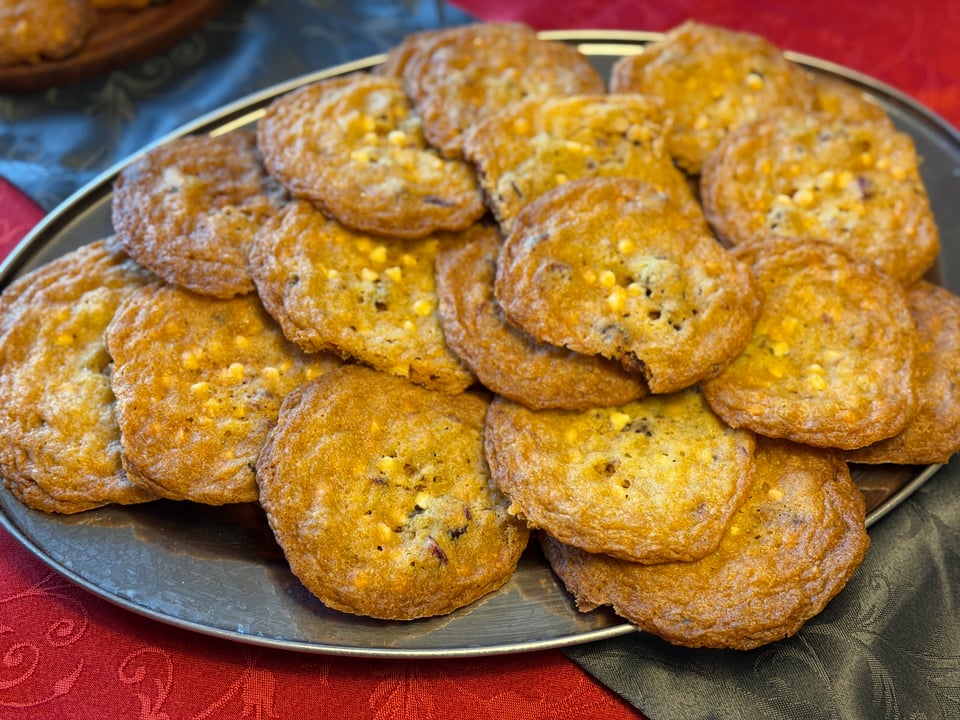 A silver colored tray is piled with White Chocolate Cranberry Orange Cookies