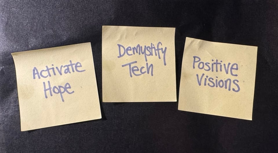 three post-it notes on a grey background with text that says: Activate Hope; Demystify Tech; and Positive Visions