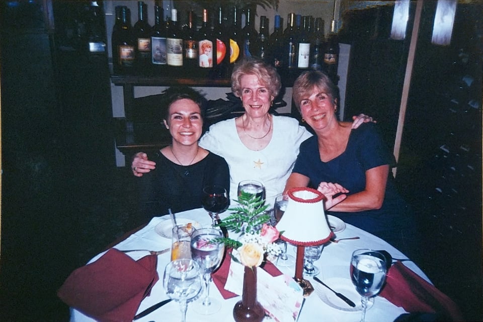 A photo at a restaurant where three generations of women sit at a table. My grandma is in the center, my mom to her right, and I'm to her left. We are all smiling.