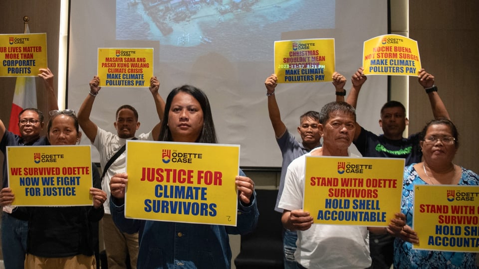 Trixy Elle, center, holds a placard reading "Justice for Climate Survivors" alongside fellow Typhoon survivors during a Greenpeace-organized press conference.