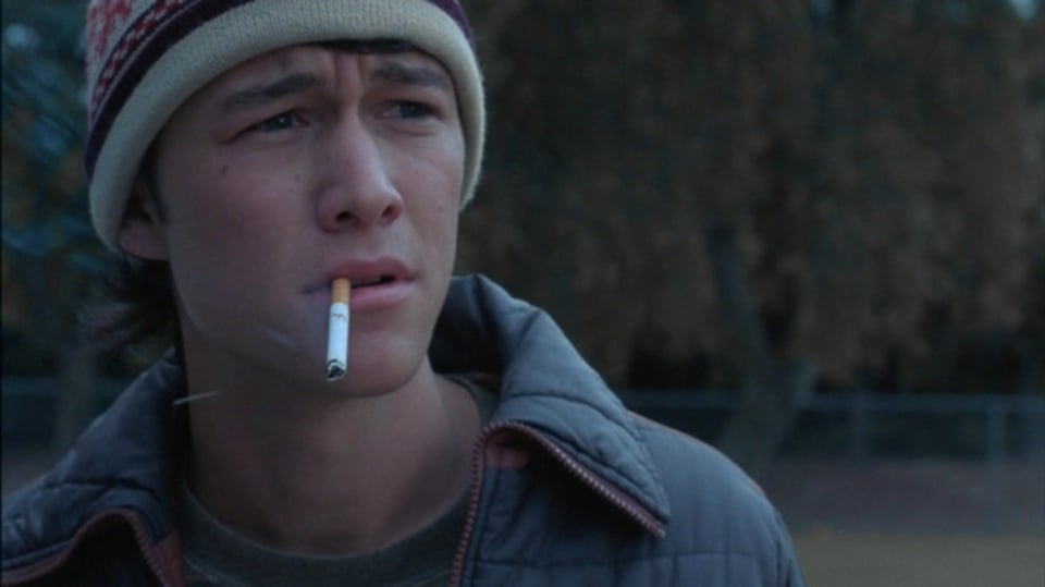 An image of Joseph Gordon Levitt in the film adaptation of Mysterious Skin. Levitt looks stricken and upset, he's wearing a wool hat and has a cigarett dangling from his lips