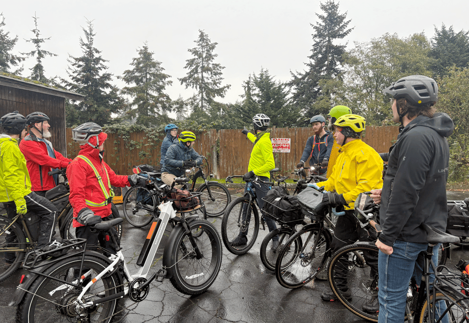 Tour attendees with bikes look at a point of interest near a road.