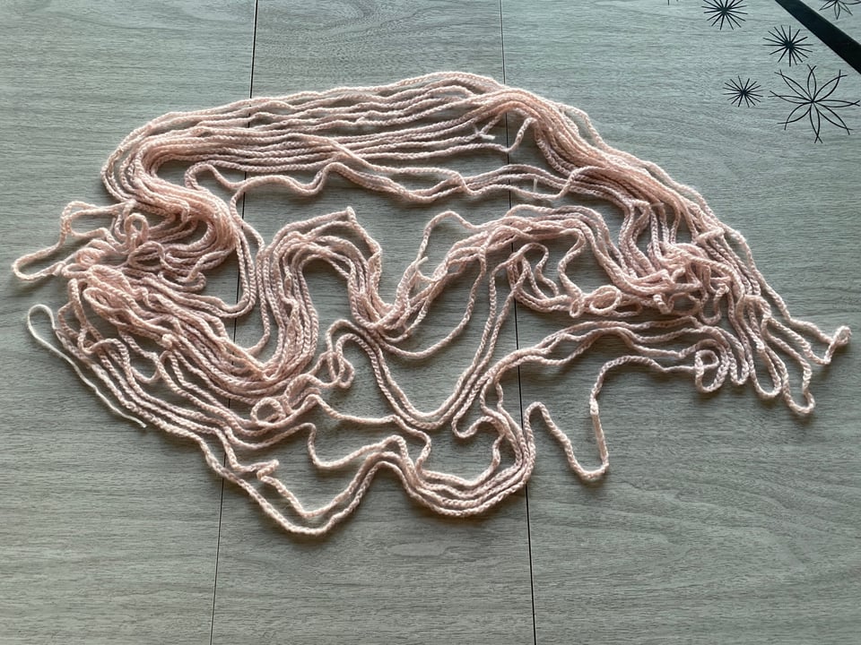 a pile of pale pink yarn that has been crocheted with one simple stitch
