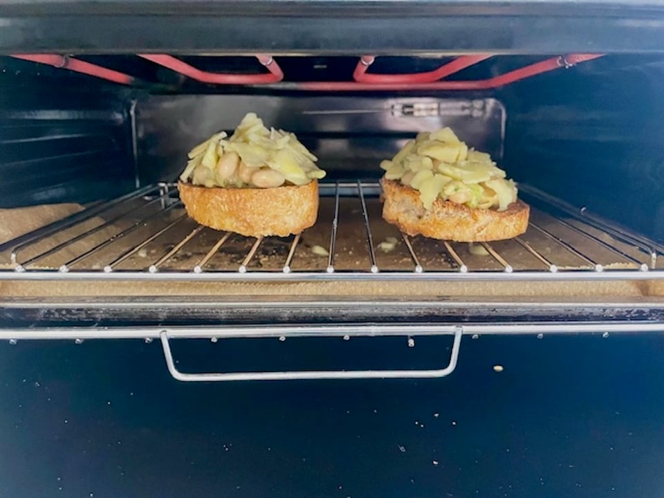 Two slices of cheesy beany melt under the grill