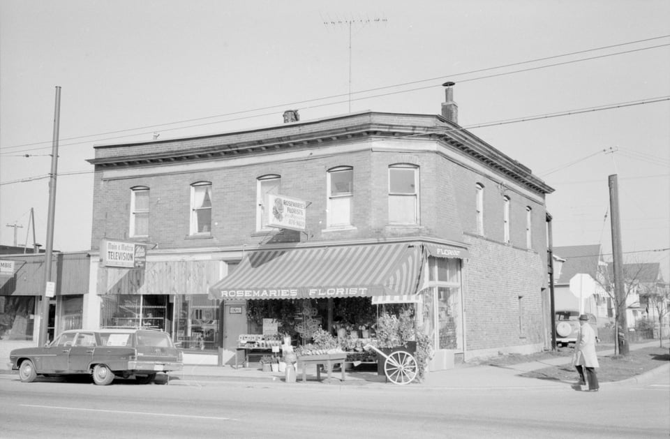 Black and white street scene of a 2 story building with "Rosemarie's Florist" on ground level.