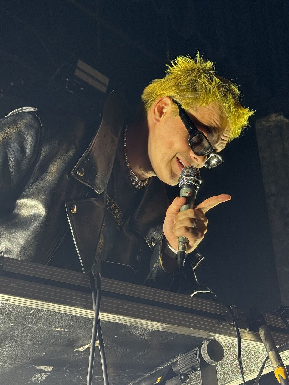 George Clanton on stage holding a microphone, wearing sunglasses and a leather jacket