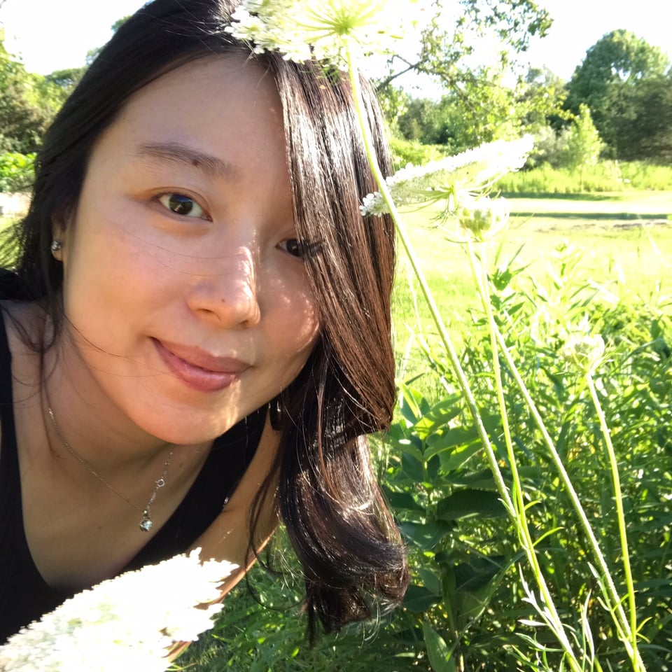 Jessica Koehler sits in a field with flowers.