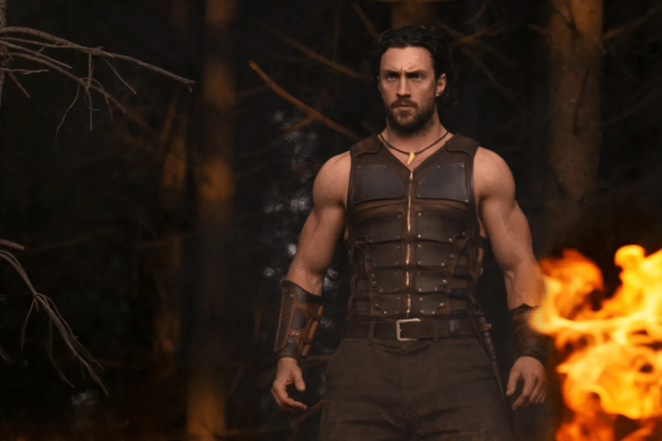 Kraven the Hunter, a buff guy wearing leather armor that appears to be all straps, with exposed muscley arms. He does not believe in shaving or haircuts