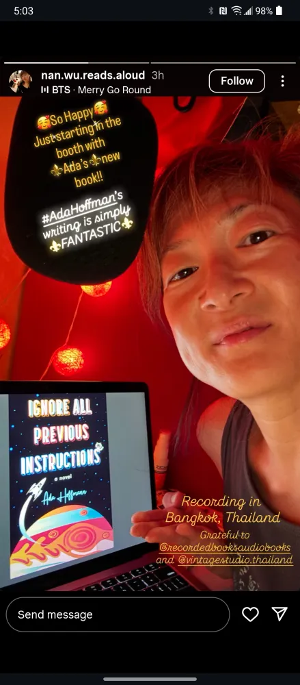 Screenshot from n.wu.reads.aloud on Instagram. Nancy Wu, a Chinese woman in a tank top, poses in front of a red backdrop with a laptop showing the cover art of Ignore All Previous Instructions. Yellow lanterns can be seen overhead. Bubbles of text in the image say: "So happy. Just starting in the booth with Ada's new book! Ada Hoffmann's writing is simply fantastic. Recording in Bangkok, Thailand. Grateful to @recordedbooks audiobooks and @vintagestudio.thailand"