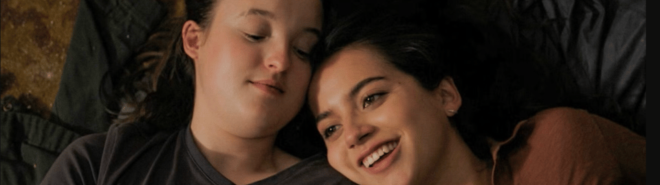 A screenshot from The Last of us Season 2. It depicts Bella Ramsay and Isabella Merced's characters lying together, looking loved up.