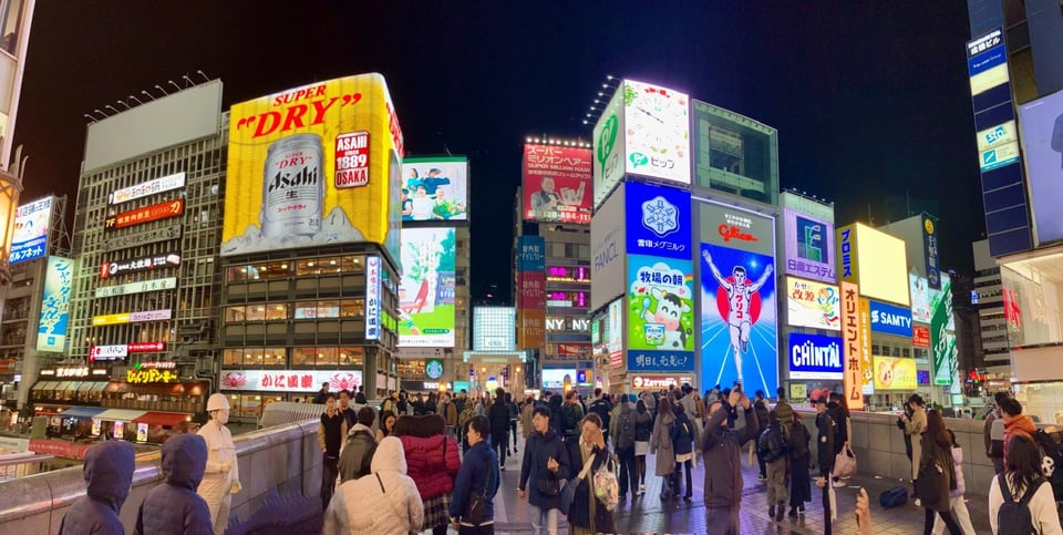 A an overwhelming sea of people, lights and billboards in Dotonbori, Osaka, at night.